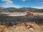 Bomberos del CEIS y agente medioambiental apagan una quema de plsticos junto al monte, en Aledo